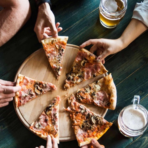 people grabbing a piece of pizza